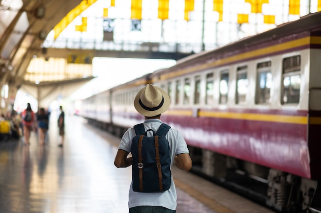 Jeune homme voyageur avec sac à dos en attente de train