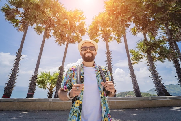 Jeune homme voyageur en vacances d'été avec de beaux palmiers et des paysages marins en arrière-plan