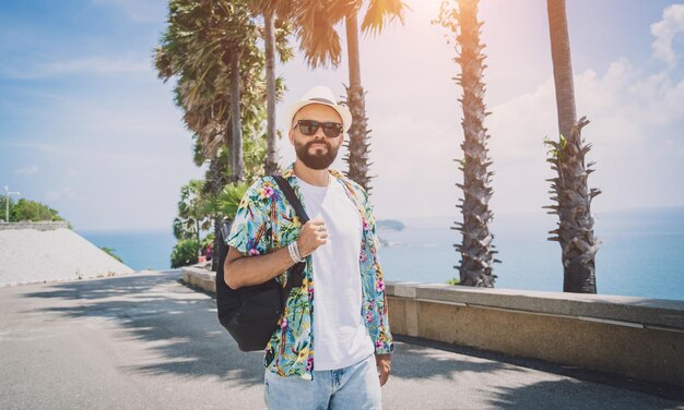 Jeune homme voyageur en vacances d'été avec de beaux palmiers et des paysages marins en arrière-plan