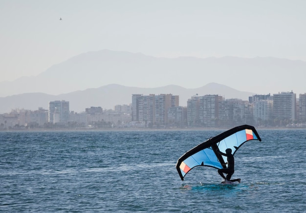 Jeune homme avec wingfoil sur la plage