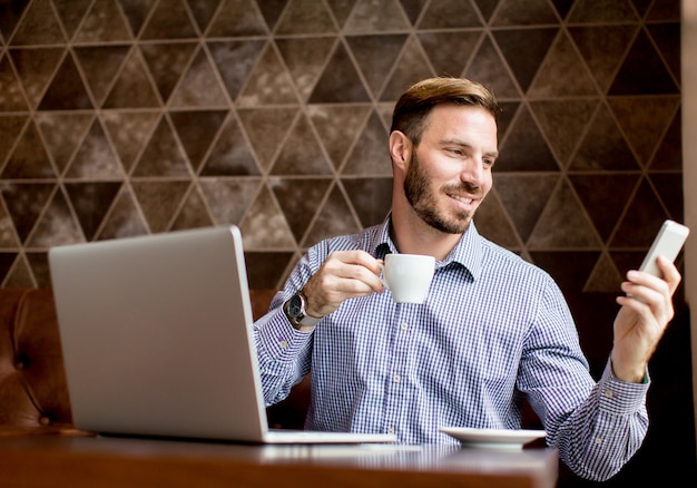 Jeune homme workin sur ordinateur portable dans le café