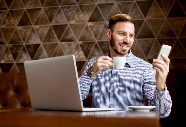 Jeune homme workin sur ordinateur portable dans le café