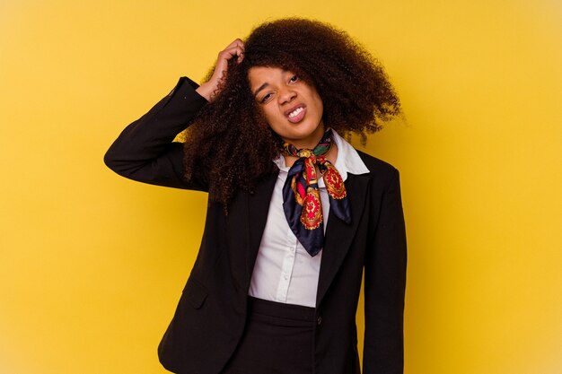 Jeune hôtesse de l'air afro-américaine isolée sur fond jaune étant choquée, elle s'est souvenue d'une réunion importante.