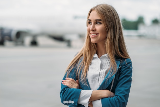 Jeune hôtesse de l'air en uniforme sur le parking des avions