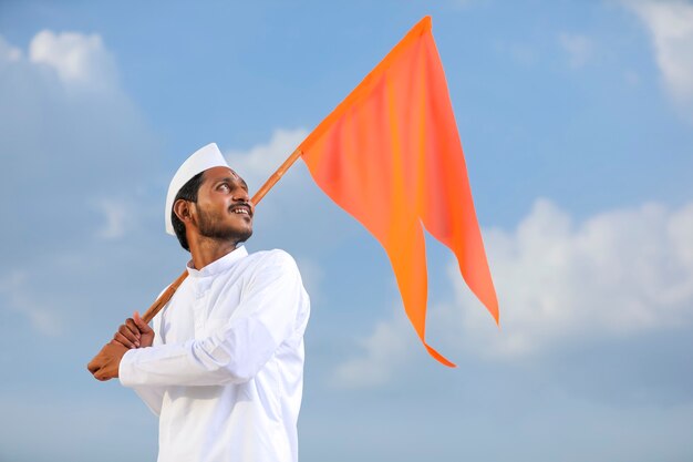 Jeune indien (pèlerin) en tenue traditionnelle et agitant un drapeau religieux.