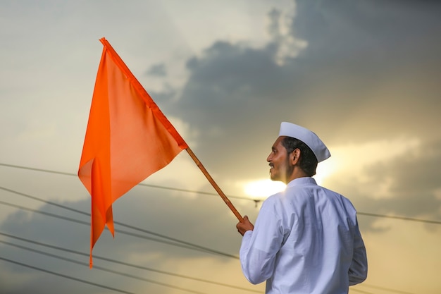 Jeune indien (pèlerin) en tenue traditionnelle et agitant un drapeau religieux.