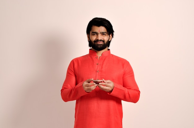 Jeune indien tenant Diya pour Diwali et portant une kurta orange