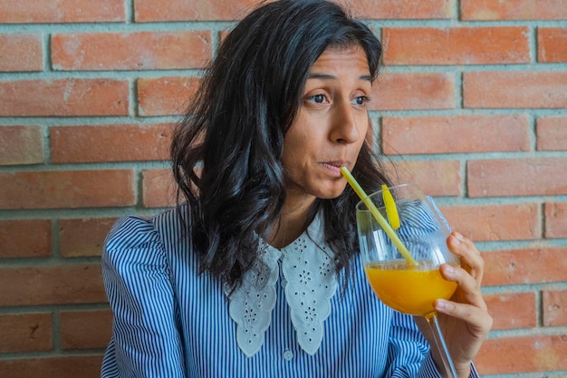 Photo une jeune indienne buvant du jus d'orange.