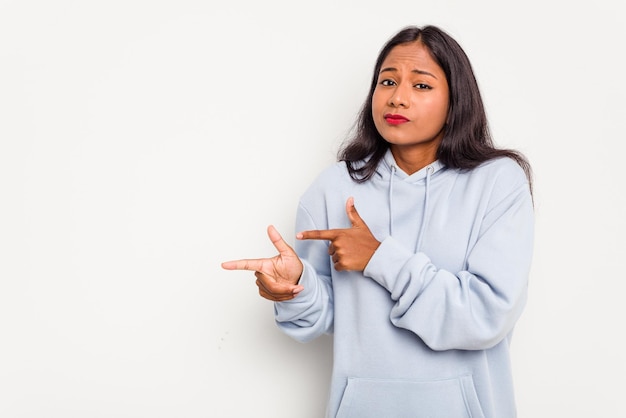 Une jeune Indienne isolée sur un fond blanc est choquée en montrant avec l'index un espace de copie.