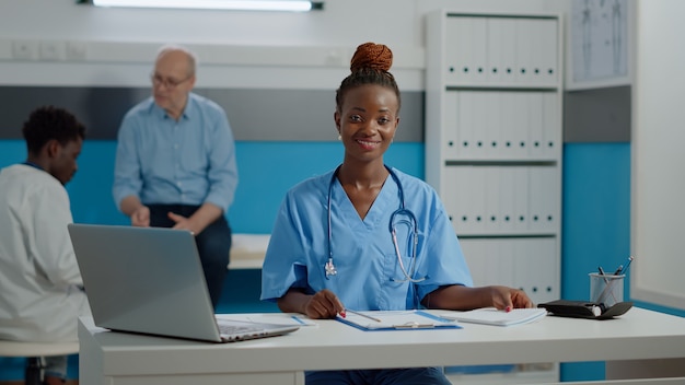 Photo jeune infirmière adulte assise au bureau avec ordinateur portable