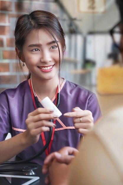 Une jeune infirmière asiatique parle de médicaments avec un patient