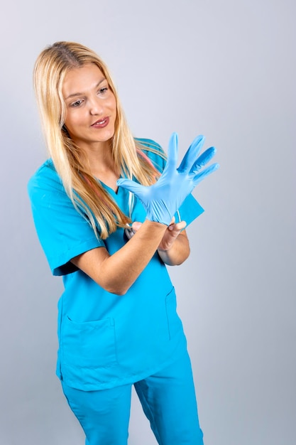 La jeune infirmière blonde met des gants bleus