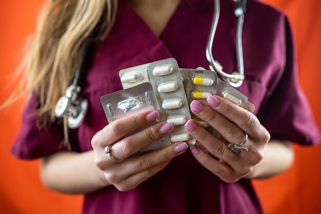 Jeune infirmière fille tenant une bouteille de médicament dorée isolée sur fond de studio monochrome