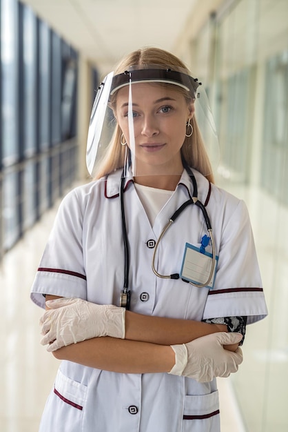 Une jeune infirmière se tient dans le couloir et tient un stéthoscope