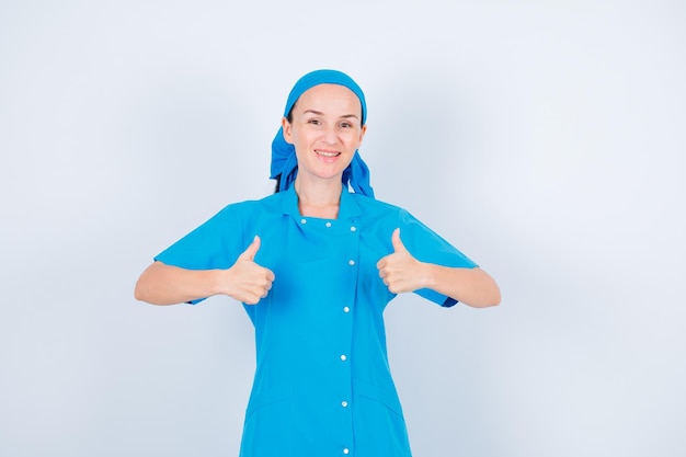 Une jeune infirmière souriante regarde la caméra en montrant un geste parfait sur fond blanc