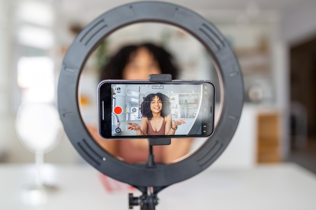 Jeune influenceuse utilisant son smartphone pour filmer un post de vlog