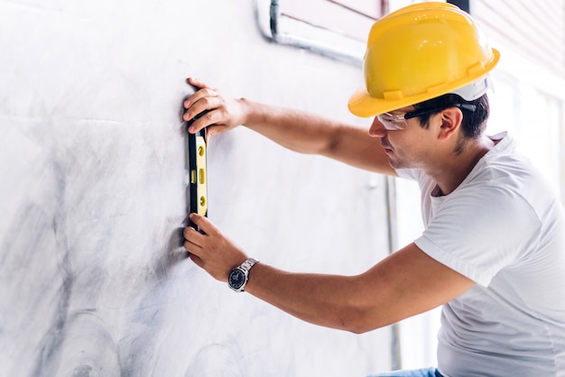 Jeune ingénieur en construction dans un casque jaune travaillant et prenant des mesures