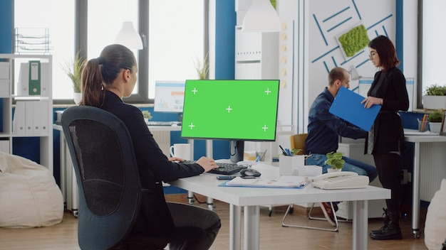 Jeune ingénieur avec écran vert horizontal à l'aide d'un clavier au bureau de l'entreprise. Femme d'affaires travaillant sur ordinateur avec modèle de maquette et arrière-plan isolé pour clé chroma au bureau.