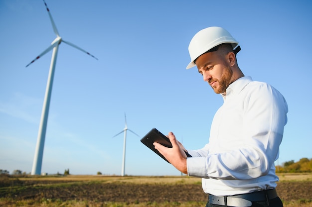 Jeune ingénieur homme regardant et vérifiant les éoliennes sur le terrain