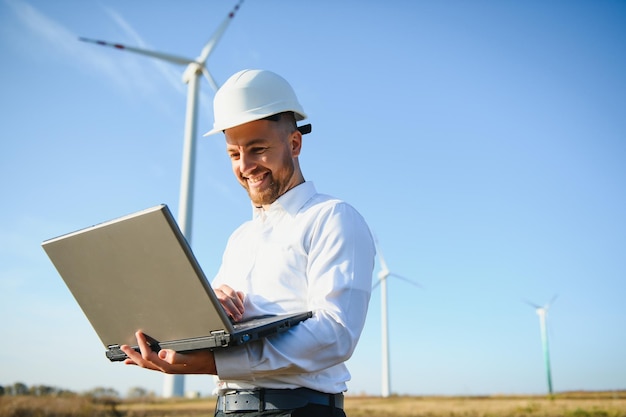 Jeune ingénieur homme regardant et vérifiant les éoliennes sur le terrain