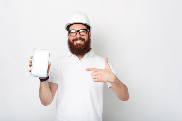 Un jeune ingénieur vêtu d'un uniforme blanc montre sa tablette.