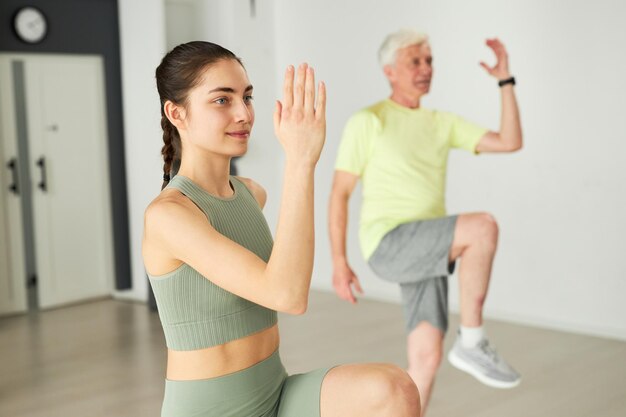 Jeune instructeur de fitness faisant de l'exercice avec des personnes âgées en studio