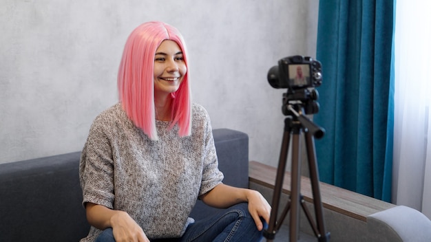 Jeune et intelligent. Belle jeune femme aux cheveux roses en tenue décontractée lors de l'enregistrement vidéo blod