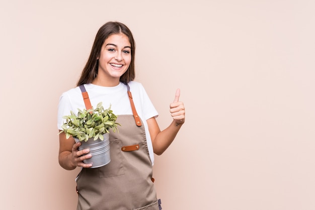 Jeune, jardinier, caucasien, femme, tenue, a, plante, isolé, sourire, et, lever, pouce haut