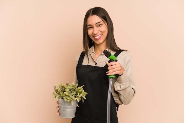 Le jeune jardinier colombien tient une plante et un tuyau, nourrissant la nature.