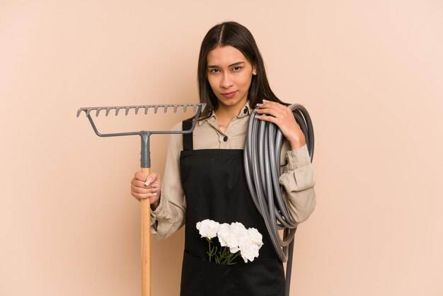 Le jeune jardinier colombien tient une plante et un tuyau, nourrissant la nature.