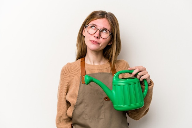 Jeune jardinier femme tenant un arroseur isolé sur fond blanc rêvant d'atteindre des objectifs et des buts