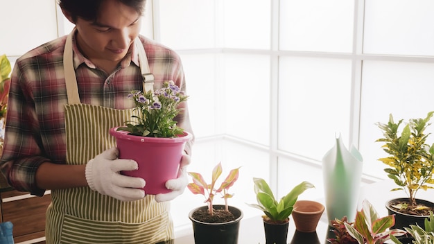 Jeune jardinier homme tenant un pot de fleurs dans la chambre.