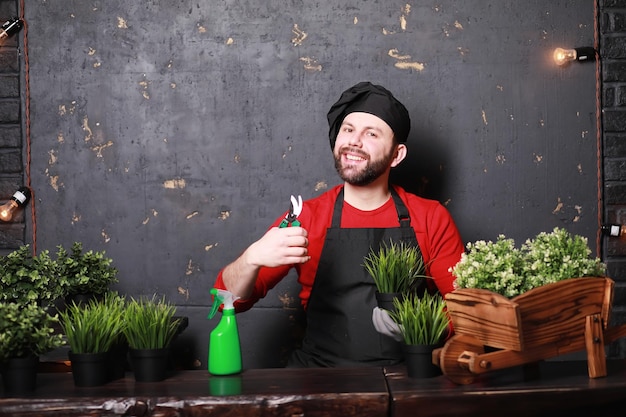 Un jeune jardinier s'occupe des semis et coupe des fleursJardinier avec un bac à fleurs Homme qui s'occupe de planter des semis au printemps