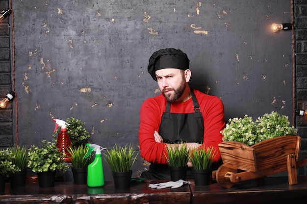 Un jeune jardinier s'occupe des semis et des fleurs coupées. Jardinier avec un bac à fleurs. Homme qui s'occupe de planter des semis au printemps.