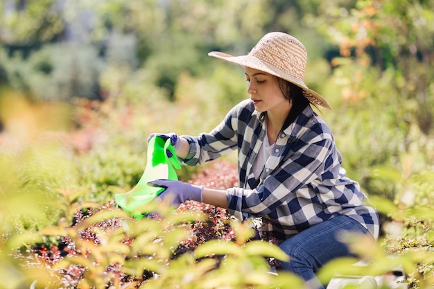 Jeune jardinière arrosant les plantes dans le jardin.