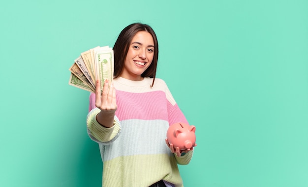 Jeune jeune femme avec une tirelire et des billets en dollars