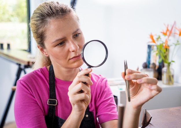 Photo jeune joaillière fabriquant des bijoux dans un atelier