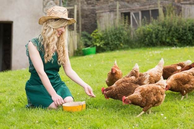 Jeune jolie blonde nourrit ses poules