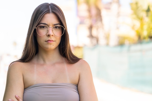 Une jeune et jolie Brésilienne à l'extérieur avec des lunettes et les bras croisés