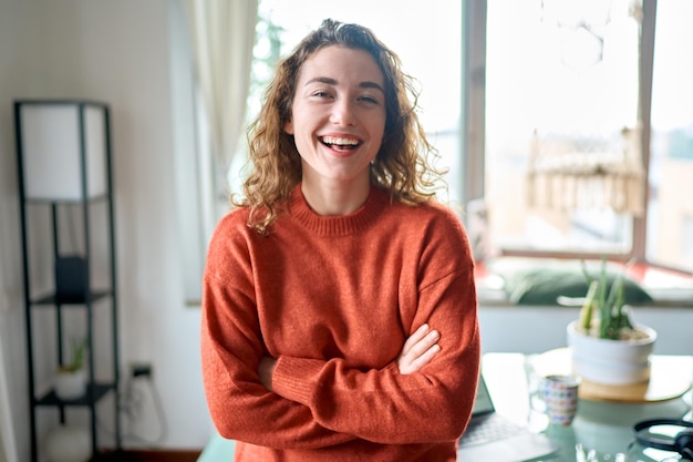 Jeune jolie dame souriante debout à la maison regardant la caméra