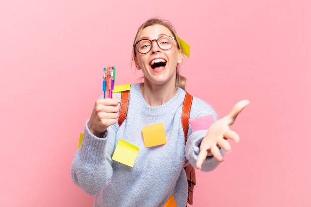 Jeune jolie étudiante avec une expression heureuse avec la main ouverte