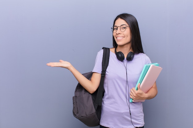 Jeune jolie étudiante latine contre mur gris