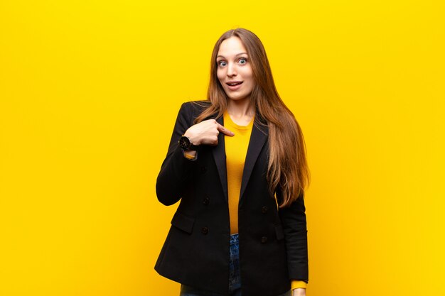 Jeune jolie femme d'affaires à l'air heureux, fier et surpris, se dirigeant gaiement vers soi-même, se sentir confiant et noble