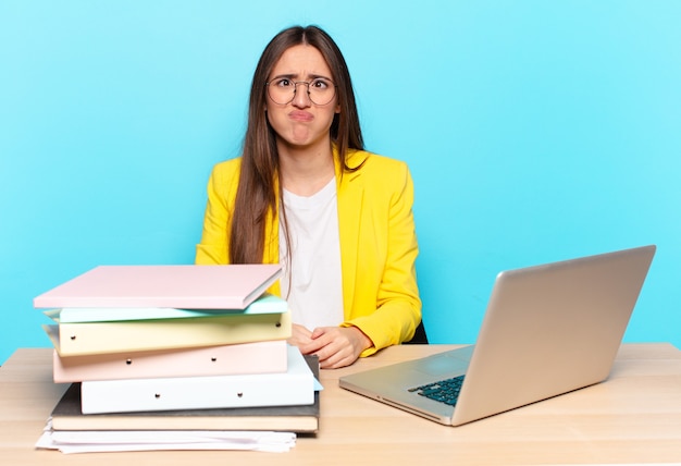 Jeune jolie femme d'affaires à l'air maladroite et drôle avec une expression stupide qui louche, plaisantant et s'amusant