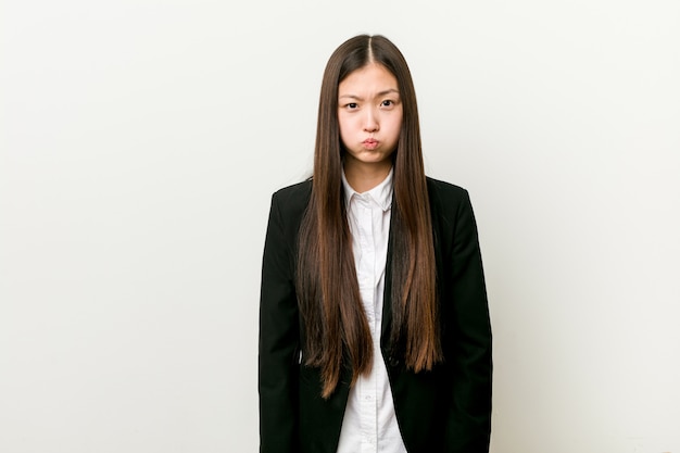 Jeune et jolie femme d'affaires chinoise se blesse aux joues, a l'air fatigué. Concept d'expression faciale.