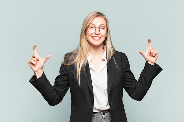 Jeune jolie femme d'affaires encadrant ou décrivant son propre sourire avec les deux mains, l'air positif et heureux, concept de bien-être