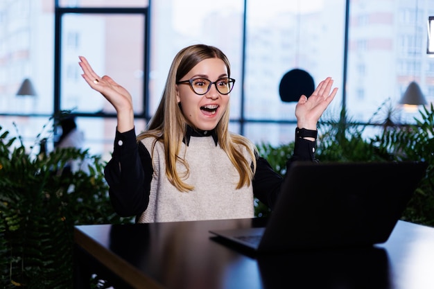 Jeune jolie femme d'affaires à lunettes travaillant au bureau devant un ordinateur portable travaille en ligne