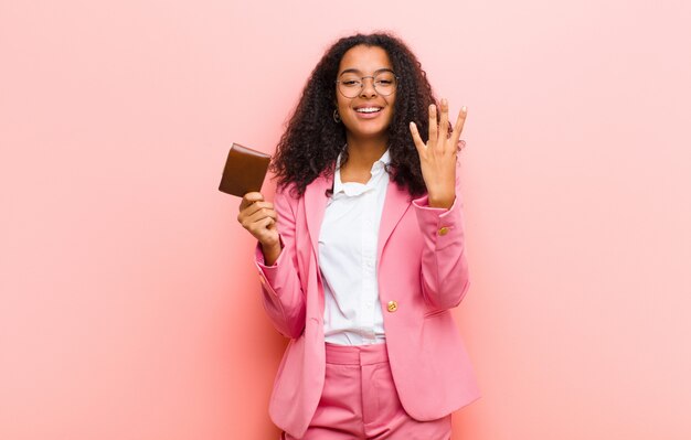 Jeune jolie femme d'affaires avec un portefeuille contre le mur rose