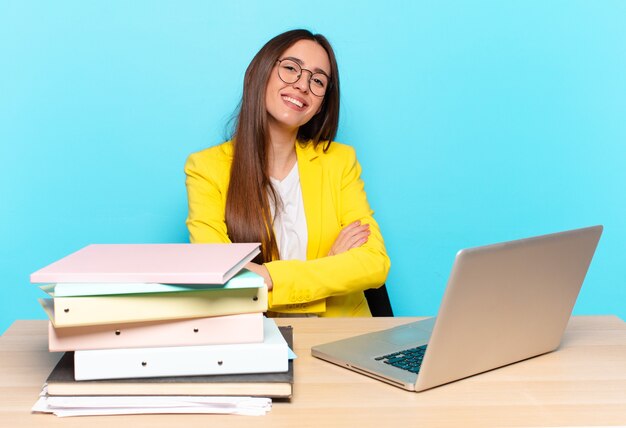 Jeune jolie femme d'affaires en riant joyeusement les bras croisés