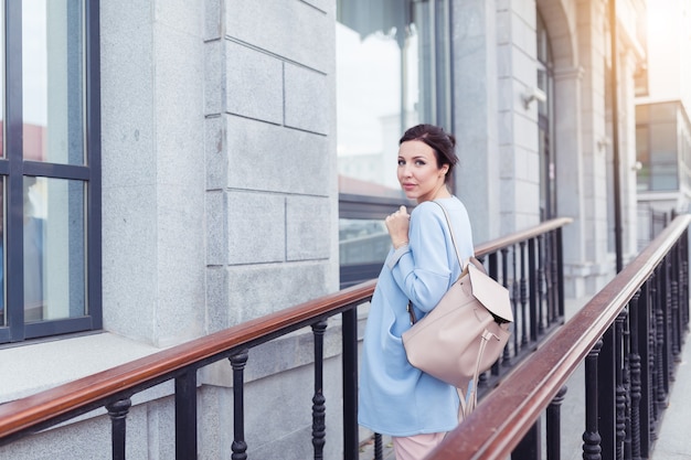 Jeune jolie femme d'affaires souriante et marchant près du bâtiment de l'entreprise. Elle marche après une rencontre réussie avec ses partenaires.